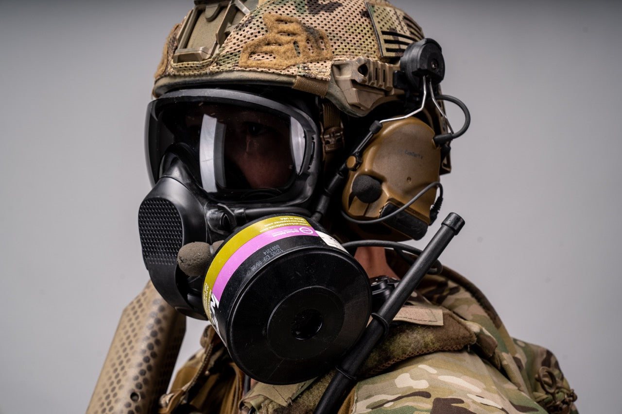Person wearing a military helmet and gas mask with a gray background
