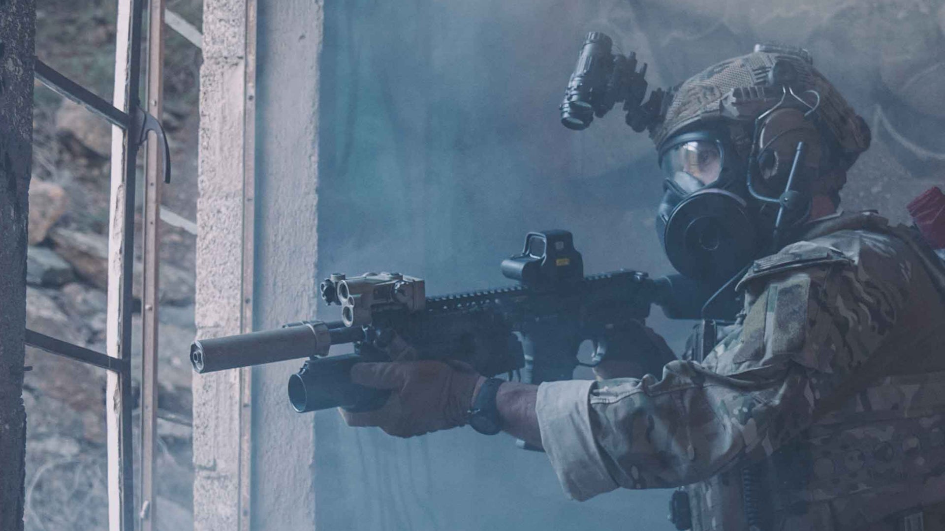 Person in military gear with a rifle, wearing a gas mask, in a foggy environment.
