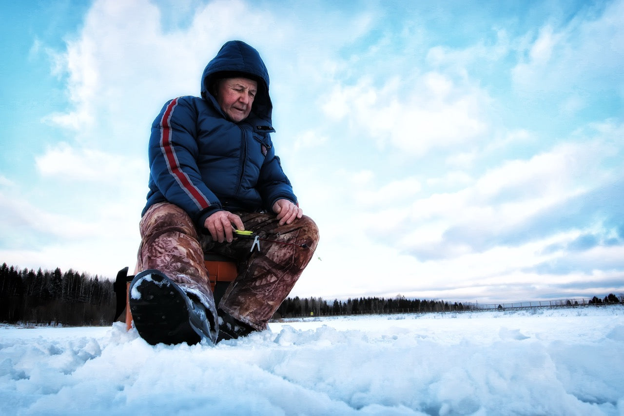 Man ice fishing in cold weather and warm boots