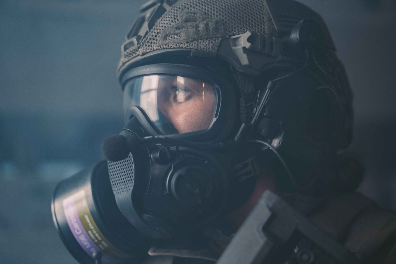 Person wearing a gas mask and helmet in a dark setting