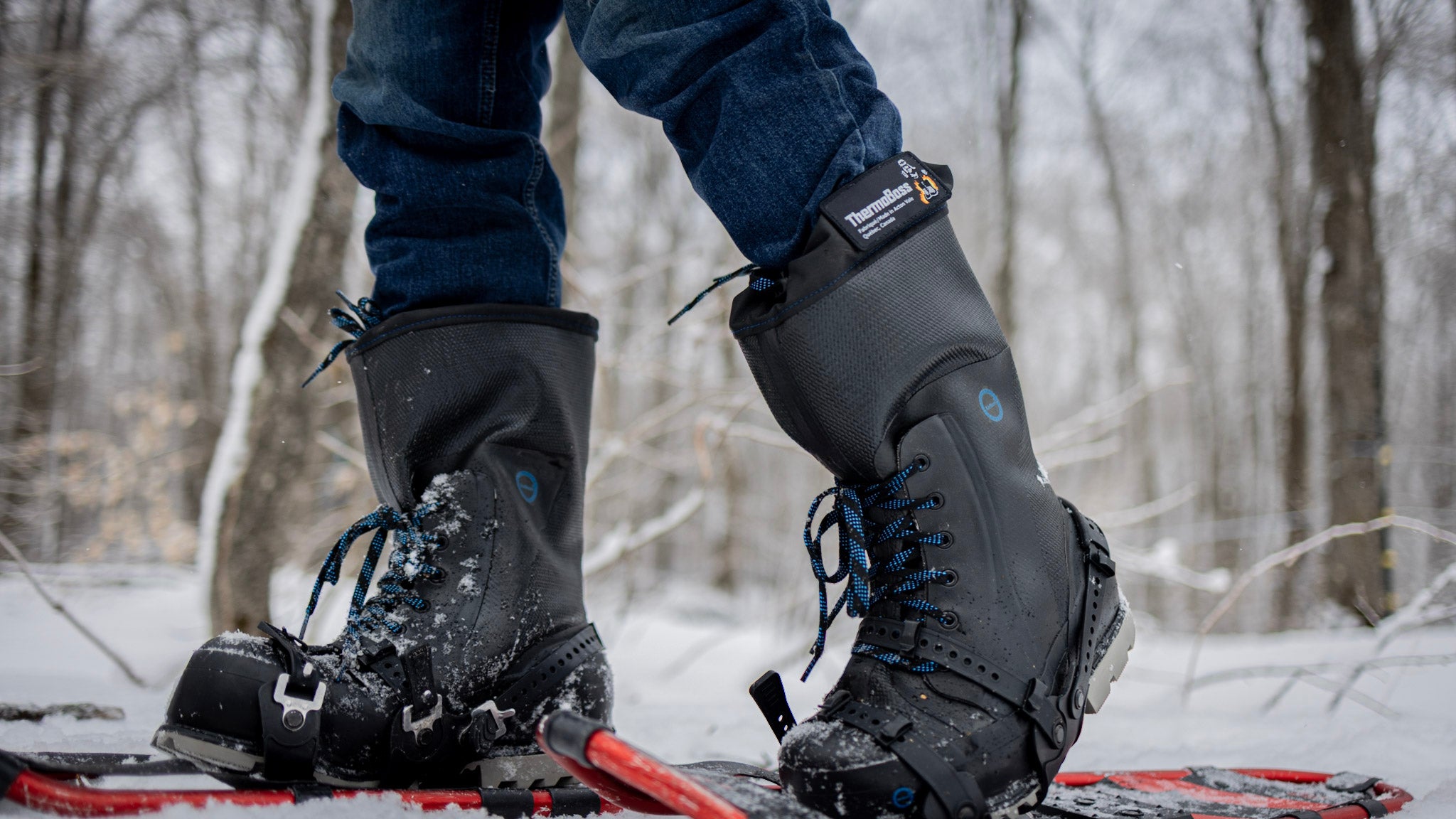 Person wearing black AirBoss ThermoBoss™ boots on a snowy landscape with trees in the background