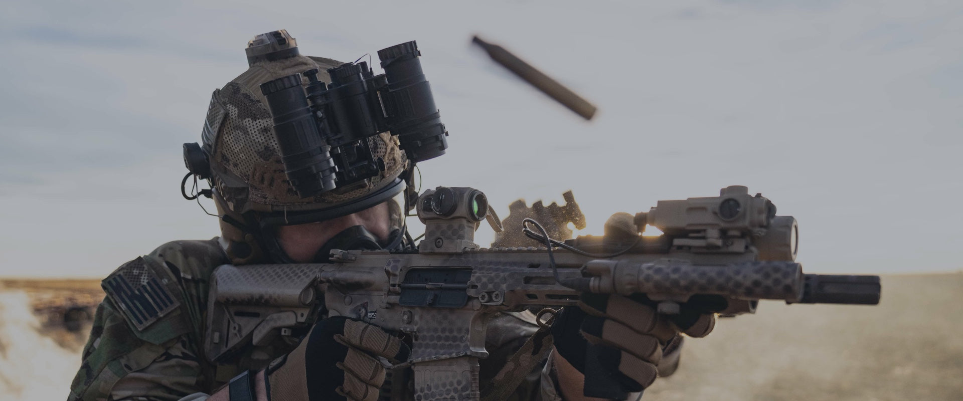 Person in military gear holding a rifle with a scope.