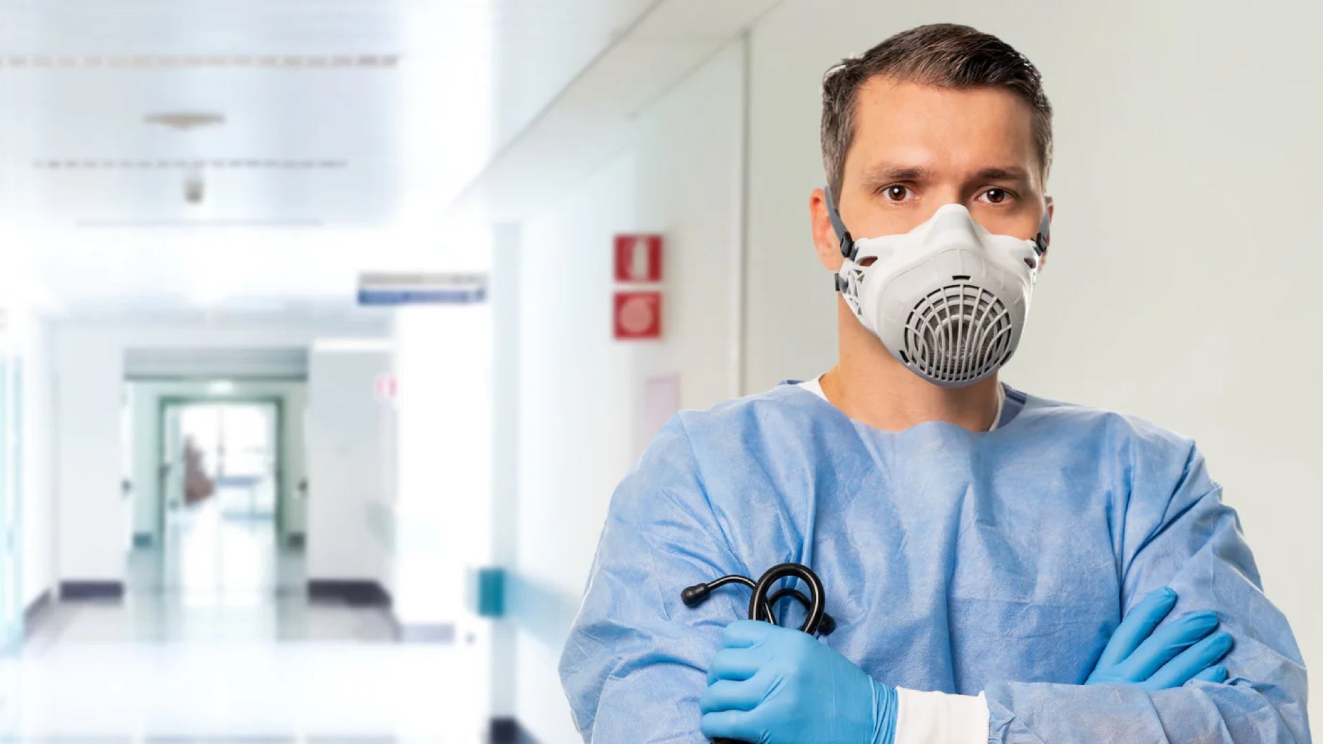 Person in medical scrubs and AirBoss 100 respirator standing in a hospital corridor